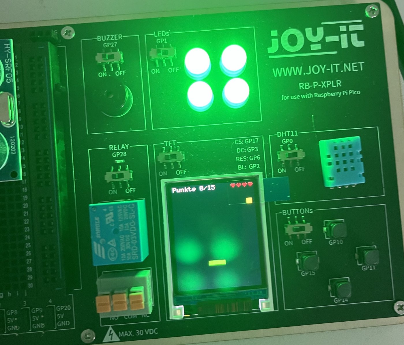 Board mit laufendem Spiel: Punkte 0/15 oben links, vier rote Herzen oben rechts, grüner Korb unten, LEDs leuchten